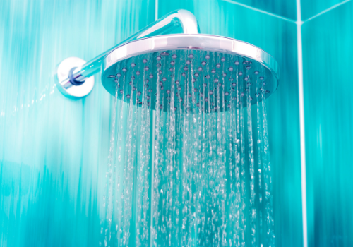 close up of waterfall shower in light water-colored bathroom