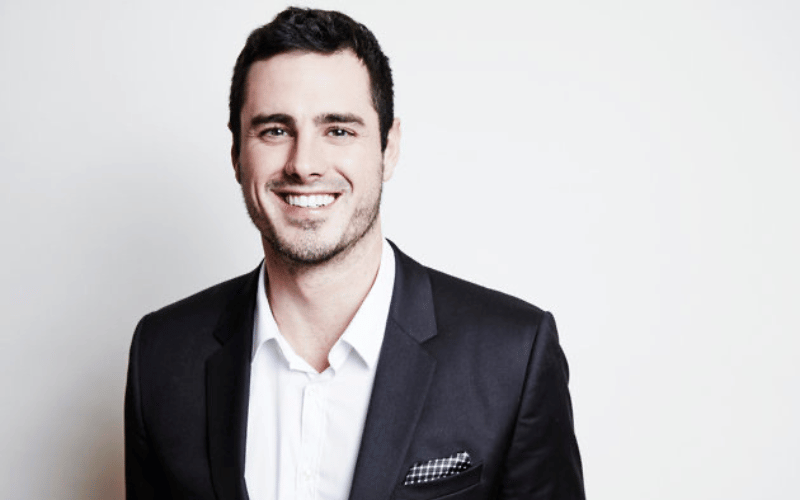 Ben Higgins wearing black suite over white background