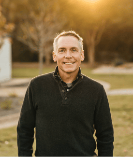 Celebrity clint harp wearing black sweater smiling outside at sunset