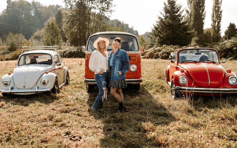 Lyndsay and Leslie standing in field in front of red old VW van.