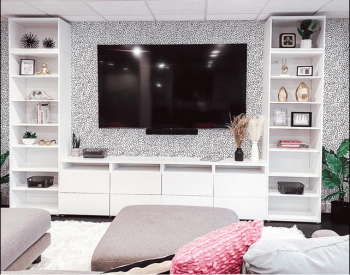 Organized and decluttered TV room with wall mounted TV and organized white modern shelving on TV console around TV