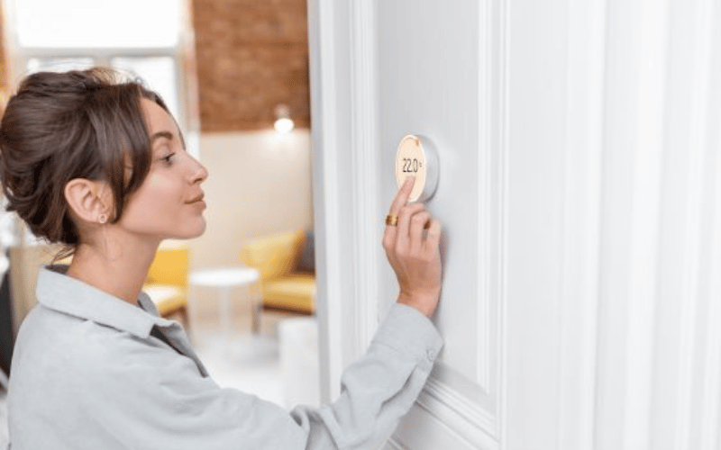 Woman programming portable touch screen HVAC system on wall 