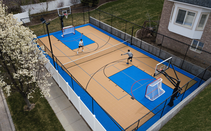 Two adult men playing pickleball on new wood and blue court birds eye view