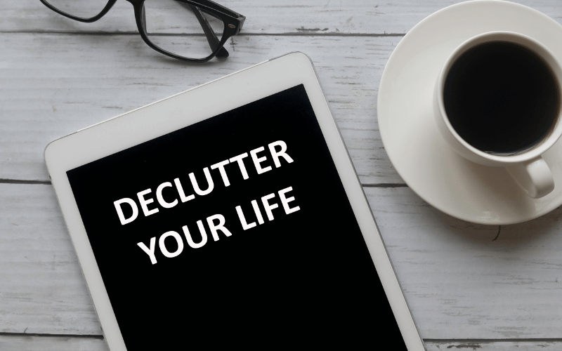 Ipad with black screen and white writing declutter your life on wooden table next to white coffee cup and saucer