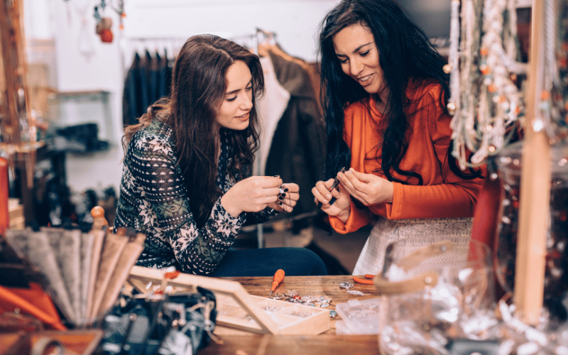Two young women looking at custom artisan jewelry in small women-owned shop