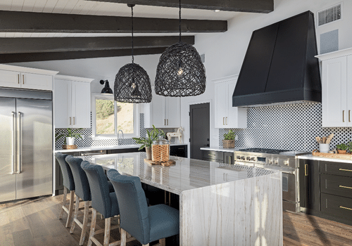 modern kitchen with stainless appliances, large breakfast bar and hanging modern black lighting, with white freshly painted cabinets