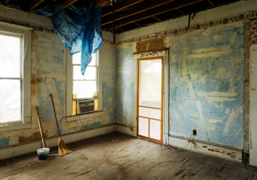 dirty unfinished room under renovation with blue plastic curtain and paint stains