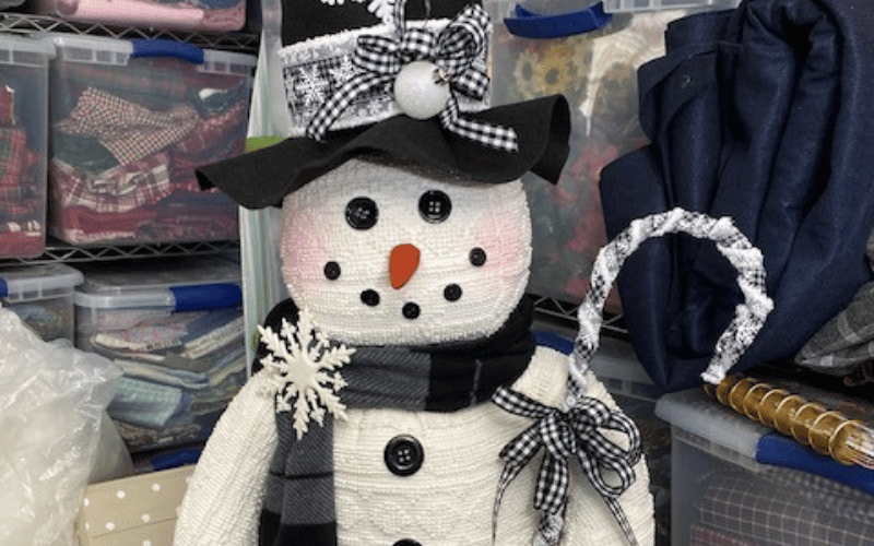 a large snowman figure holding a candy cane 