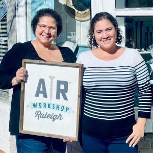 Two women business owners holding up logo sign