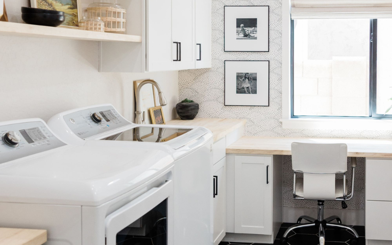 Multi purpose white room with office located next to washing machien and dryer to use more space